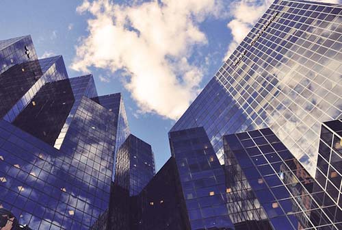 Upward perspective view of tall glass office buildlings