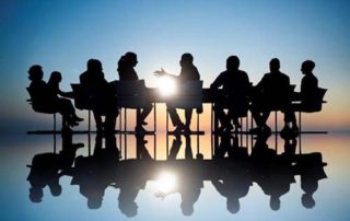 Workers in a business meeting shadowed by a background lightsource