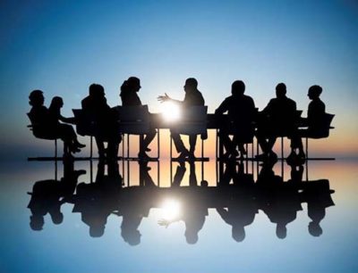 Workers in a business meeting shadowed by a background lightsource
