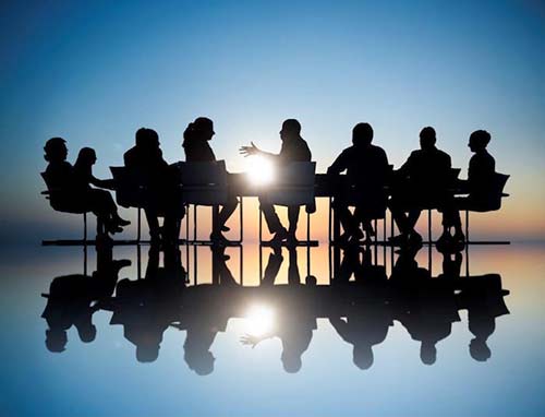 Workers in a business meeting shadowed by a background lightsource